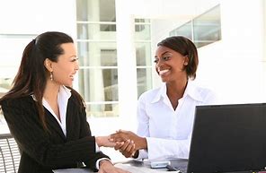 two women smilling and shaking hands